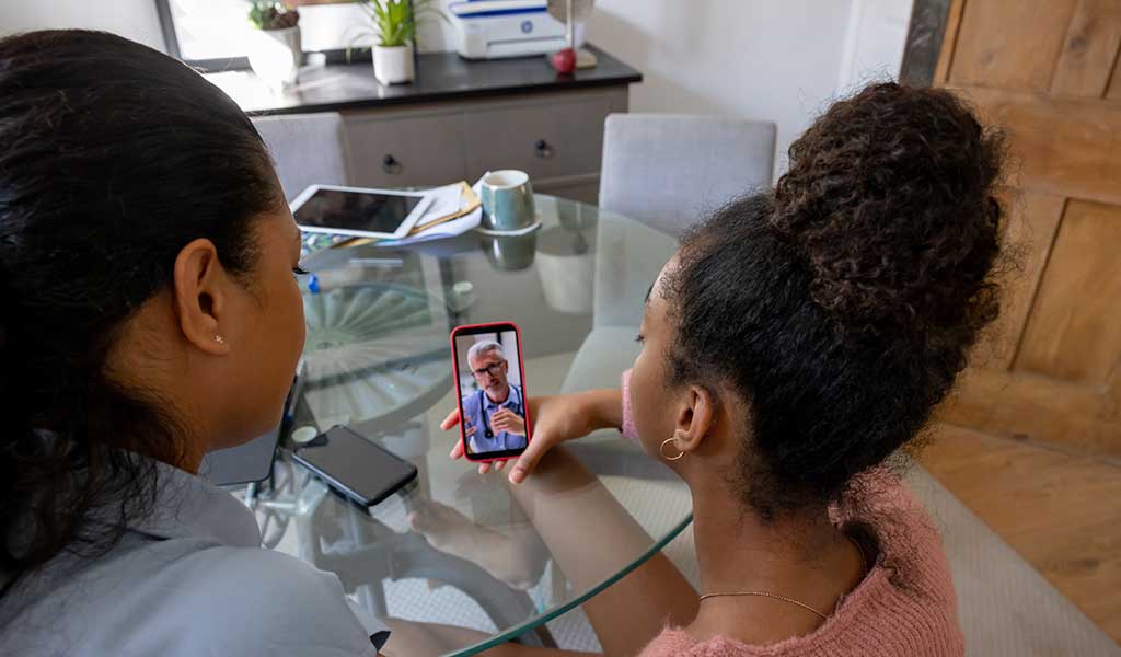 Mother and daughter at home talking to her doctor on a video call - telemedicine concepts